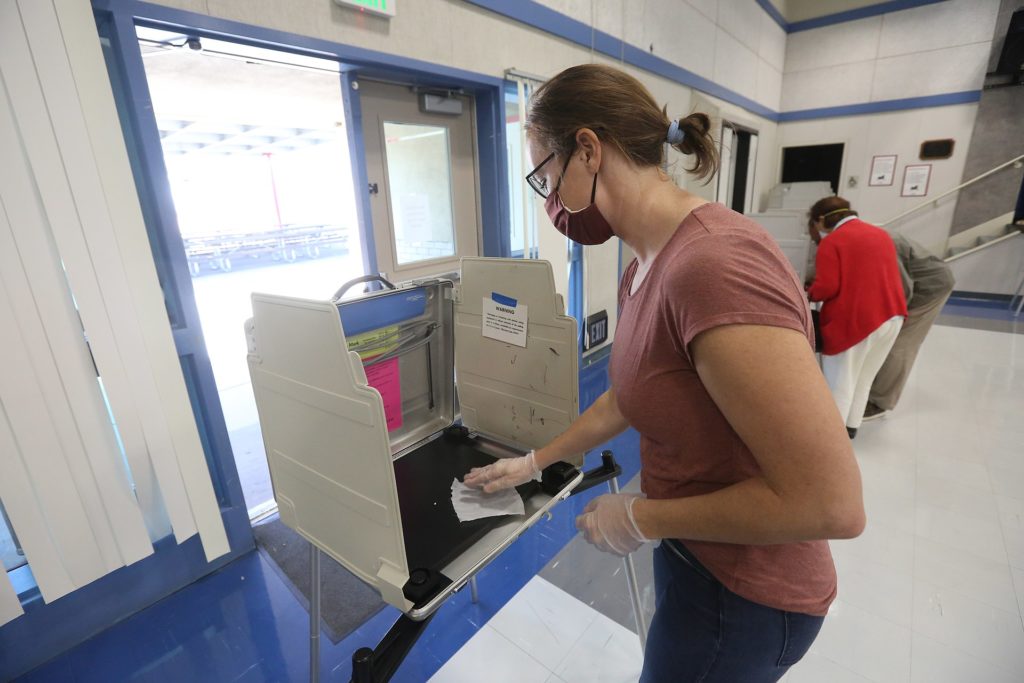 A California poll worker sanitizes a voting booth following its use at a Voter Assistance Center during the 2020 General Election.