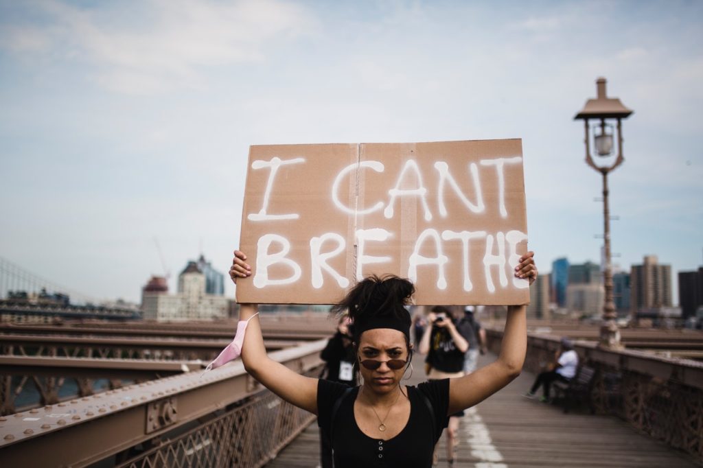 Black American woman holding a sign that says I can't breathe.